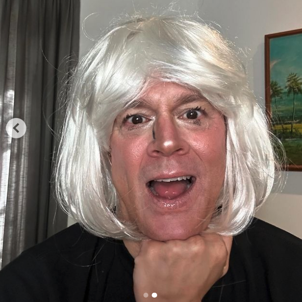 Person wearing a white wig making a playful face at the camera