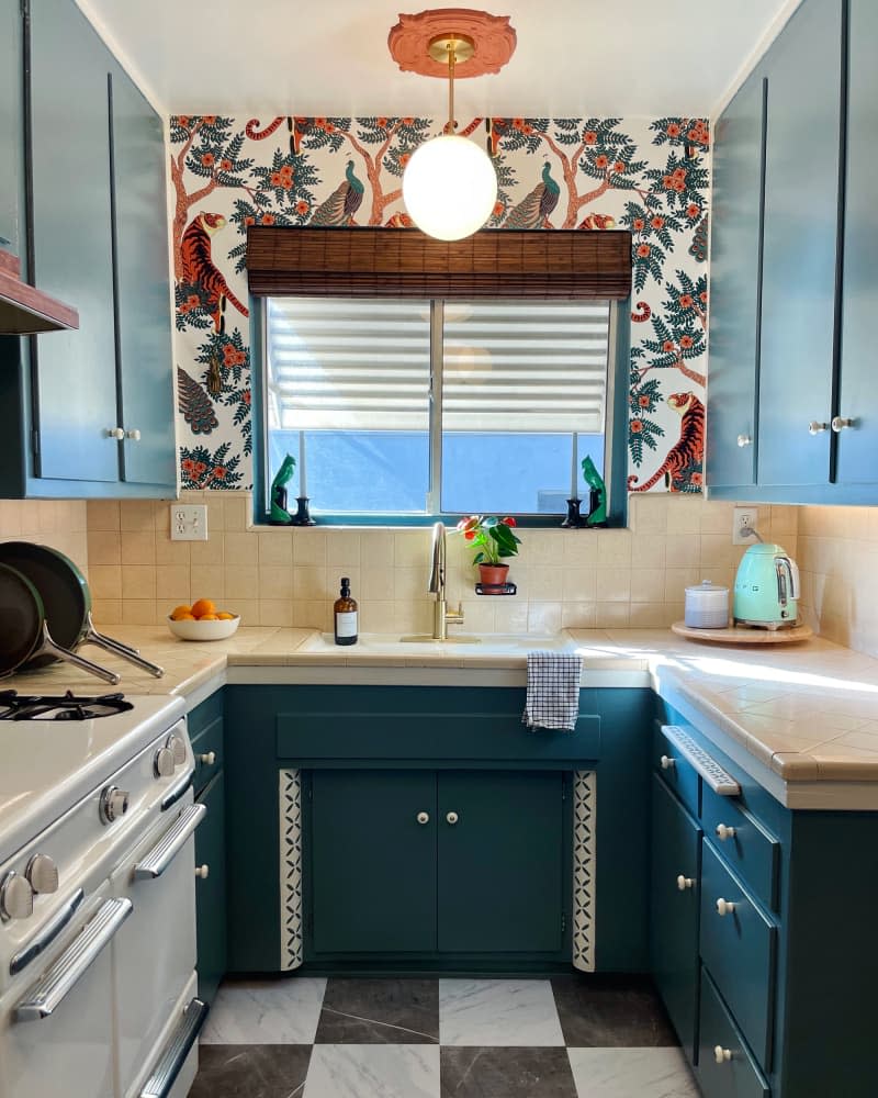 Round pendant hanging from terra cotta colored  ceiling medallion above kitchen sink.