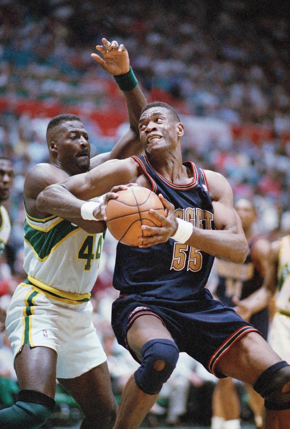 Dikembe Mutombo (55) of the Denver Nuggets spins around Michael Cage of the Seattle SuperSonics during the third quarter of their NBA playoff game in Seattle on Thursday night, April 28, 1994. Seattle beat Denver 106-82. (AP Photo/Gary Stewart)