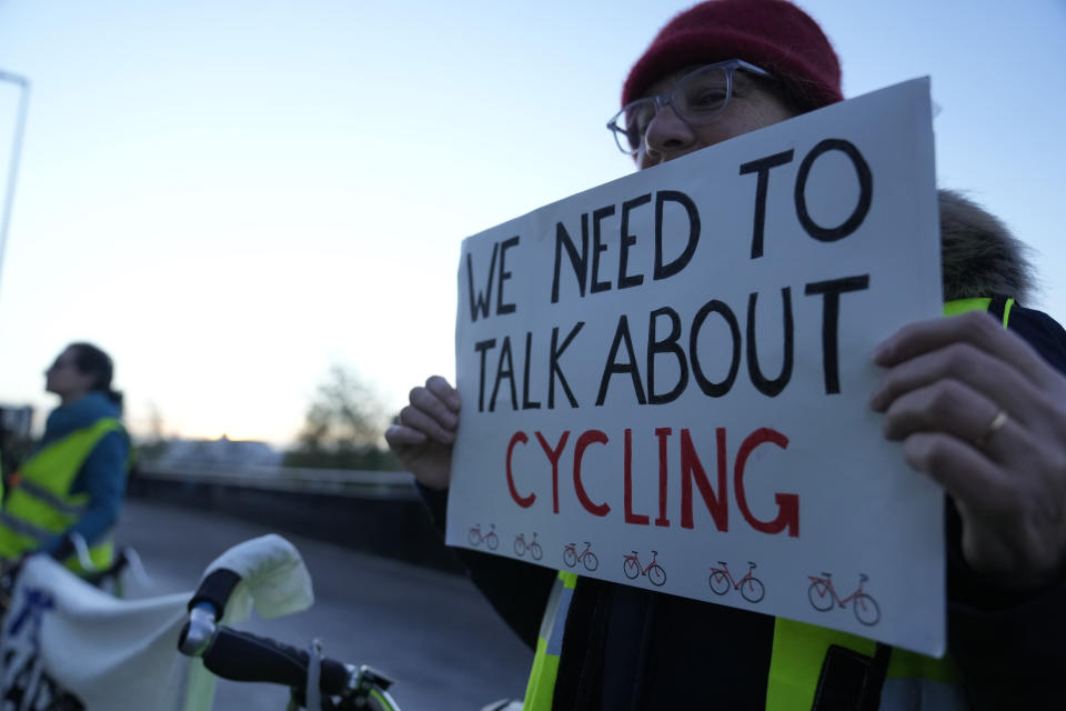 A pro-cycling demonstrator holds a protest placard outside the SEC (Scottish Event Campus) venue for the COP26 U.N. Climate Summit, in Glasgow, Scotland, Wednesday, Nov. 10, 2021. The U.N. climate summit in Glasgow has entered its second week as leaders from around the world, are gathering in Scotland's biggest city, to lay out their vision for addressing the common challenge of global warming. (AP Photo/Alastair Grant)