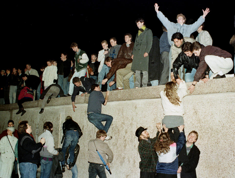 People climb the Berlin wall at the Brandenburg Gate as they celebrate the opening of the East German border Nov. 9, 1989. (Photo: Herbert Knosowski/Reuters) 