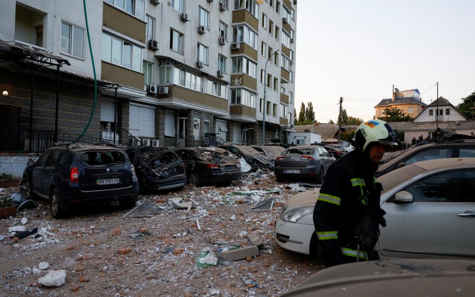 Firefighters work near cars damaged during a massive Russian drone strike