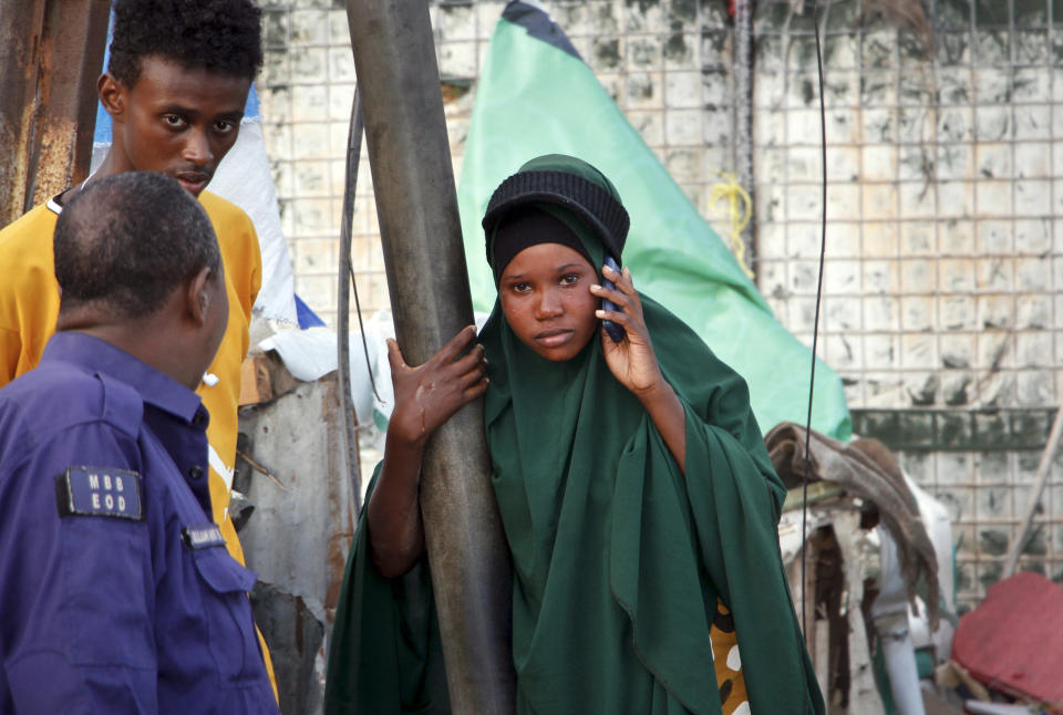 A Somali girl cries and speaks on her phone as she tries to locate her missing mother, at the scene of a bomb blast near the Sahafi hotel in the capital Mogadishu, Somalia Friday, Nov. 9, 2018. Four car bombs by Islamic extremists exploded outside the hotel, which is located across the street from the police Criminal Investigations Department, killing at least 20 people according to police. (AP Photo/Farah Abdi Warsameh)