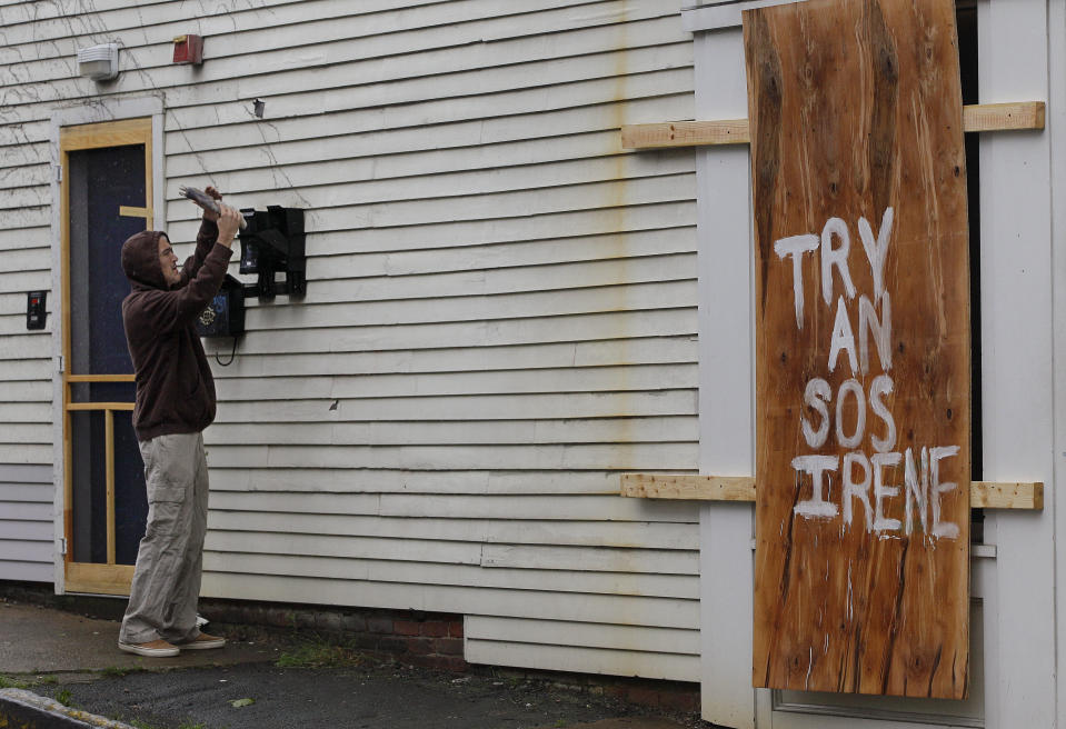 In this Aug. 28, 2011 photo, a resident of rhe neighborhood checks his mail box during the effects of hurricane Irene on Holland Street in Newport, RI., Sunday morning, A year after the remnants of Hurricane Irene blew through Rhode Island, the storm that cut power to well over half the state’s utility customers has been all but forgotten _ though a storm-related rate increase could be on the way. (AP Photo/Stephan Savoia)