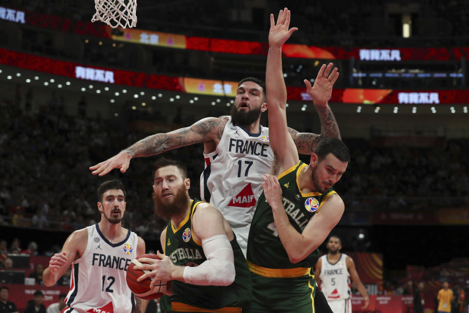 Vincent Poirier of France battles the ball with Aron Baynes and Chris Goulding of Australia during their third placing match for the FIBA Basketball World Cup at the Cadillac Arena in Beijing, Sunday, Sept. 15, 2019. (AP Photo/Ng Han Guan)