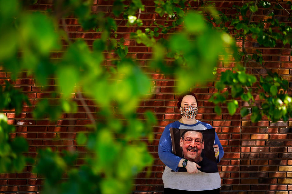 Sara Atkins poses for a photo, in Wynnewood, Pa., Tuesday, May 10, 2022, while holding a pillow with an image of her father Andy Rotman-Zaid, who died of COVID-19 in December 2020. She channels her grief into fighting for global vaccination and better access to health care to honor her father. (AP Photo/Matt Rourke)