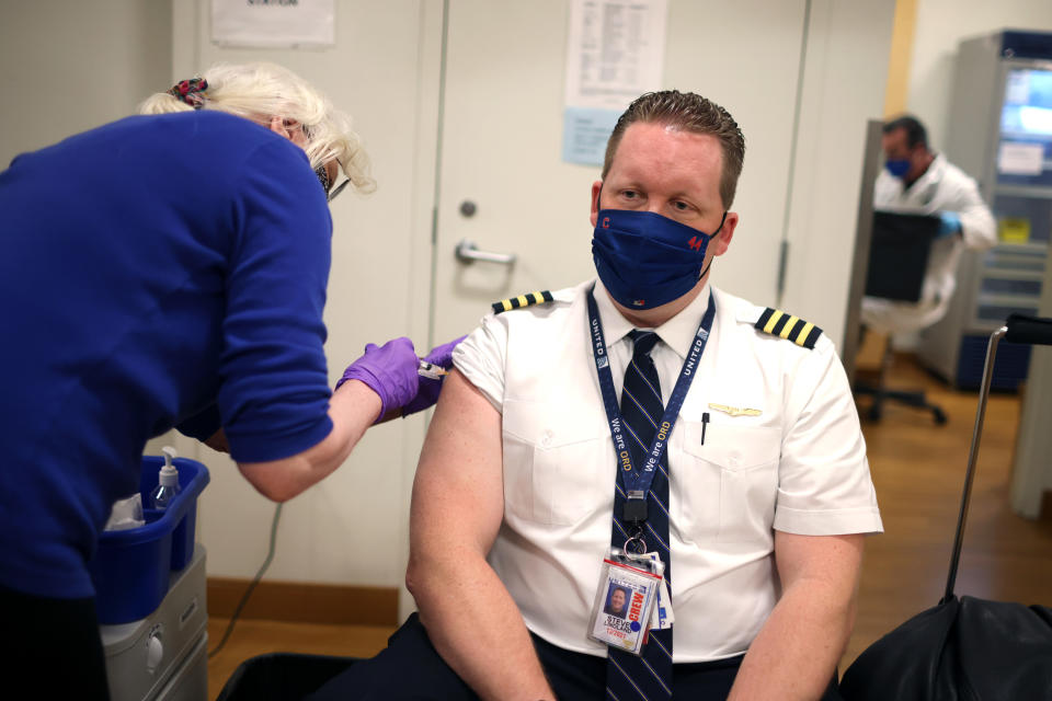 CHICAGO, ILLINOIS - MARCH 09: United Airlines pilot Steve Lindland receives a COVID-19 vaccine from RN Sandra Manella at United's onsite clinic at O'Hare International Airport on March 09, 2021 in Chicago, Illinois. United has been vaccinating about 250 of their O'Hare employees at the clinic each day for the past several days.   (Photo by Scott Olson/Getty Images)