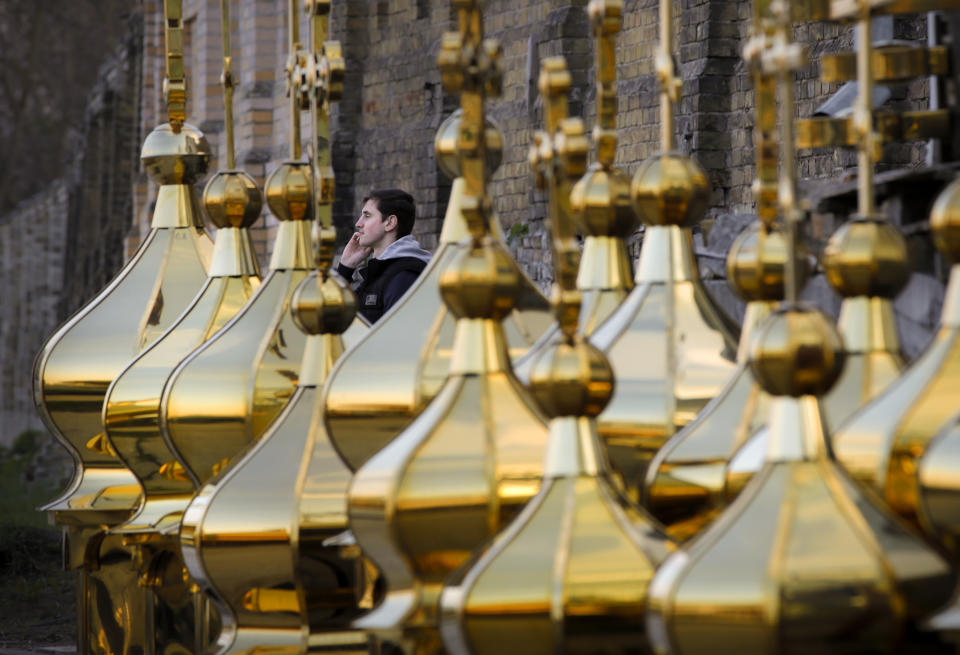 A youngster speaks on a cellphone sitting behind church construction elements for sale in Kiev, Ukraine, Wednesday, April 17, 2019. The second round of presidential vote in Ukraine will take place on April 21. (AP Photo/Vadim Ghirda)