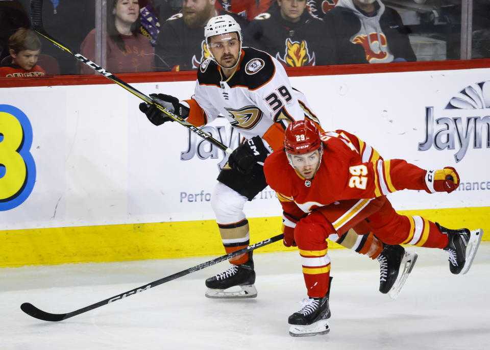 Anaheim Ducks forward Sam Carrick, left, is checked by Calgary Flames forward Dillon Dube during second-period NHL hockey game action in Calgary, Alberta, Sunday, April 2, 2023. (Jeff McIntosh/The Canadian Press via AP)