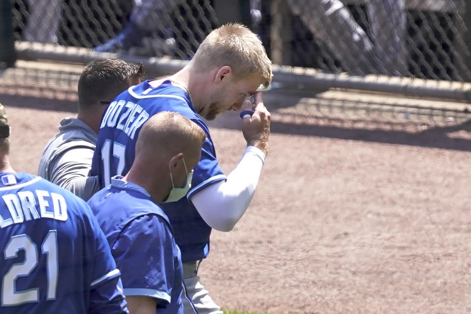 Kansas City Royals' Hunter Dozier rubs his head as he heads to the dugout after colliding with Chicago White Sox's Jose Abreu along the first base line in the second inning of the first game of a baseball doubleheader Friday, May 14, 2021, in Chicago. (AP Photo/Charles Rex Arbogast)