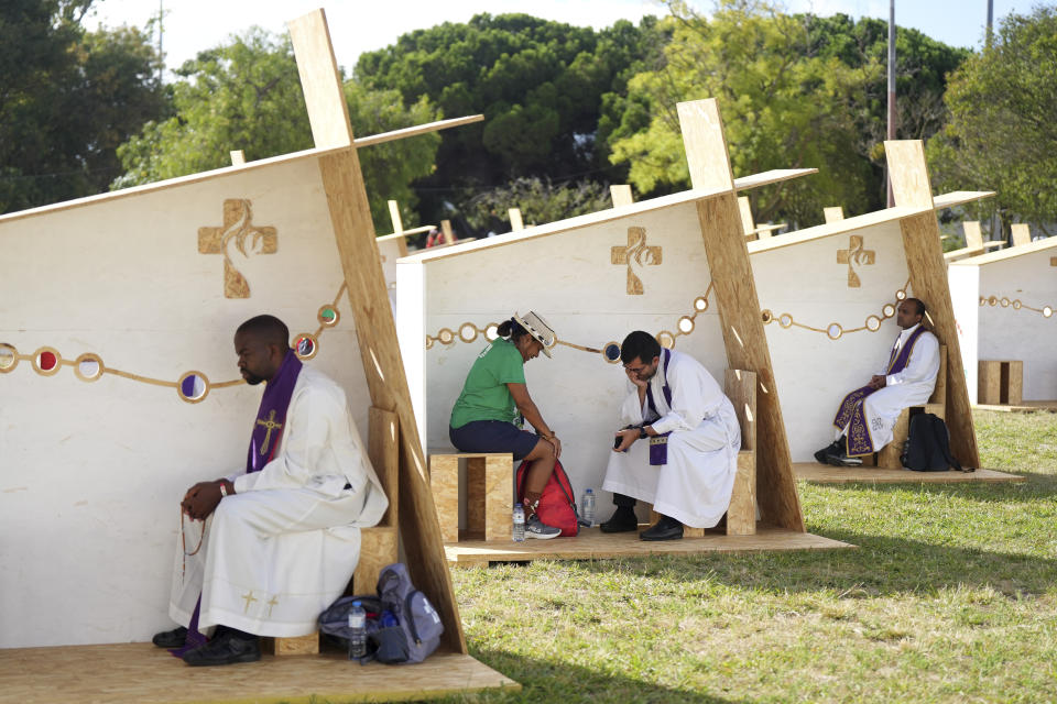 A priest listens to confession in a row of confessionals set up for pilgrims arriving for international World Youth Day at a park in Lisbon, Tuesday, Aug. 1, 2023. Pope Francis will arrive Aug. 2 to attend the event that is expected to bring hundreds of thousands of young Catholic faithful to Lisbon and goes on until Aug. 6. (AP Photo/Ana Brigida)