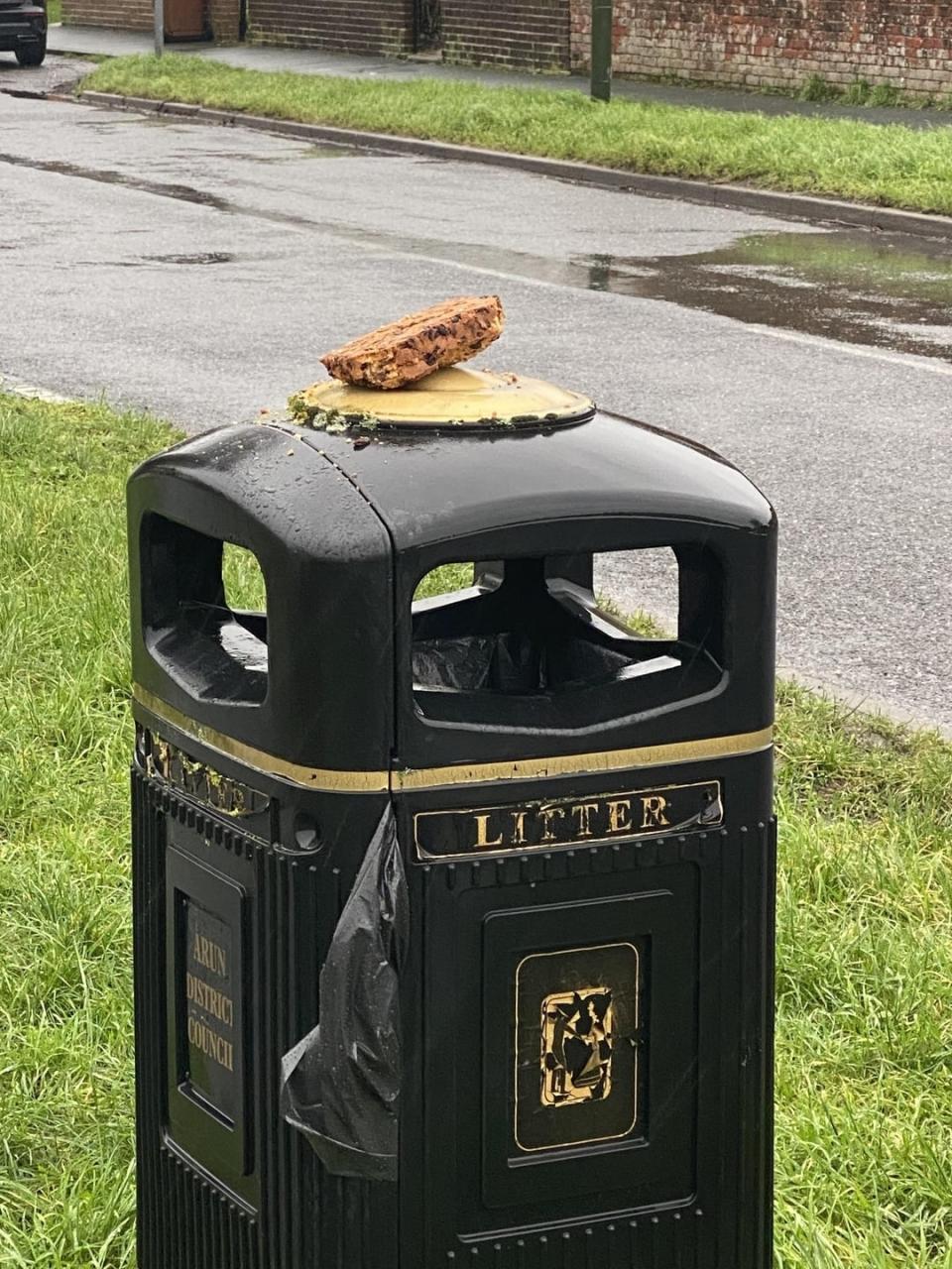 A slice of pizza on top of a public litter bin