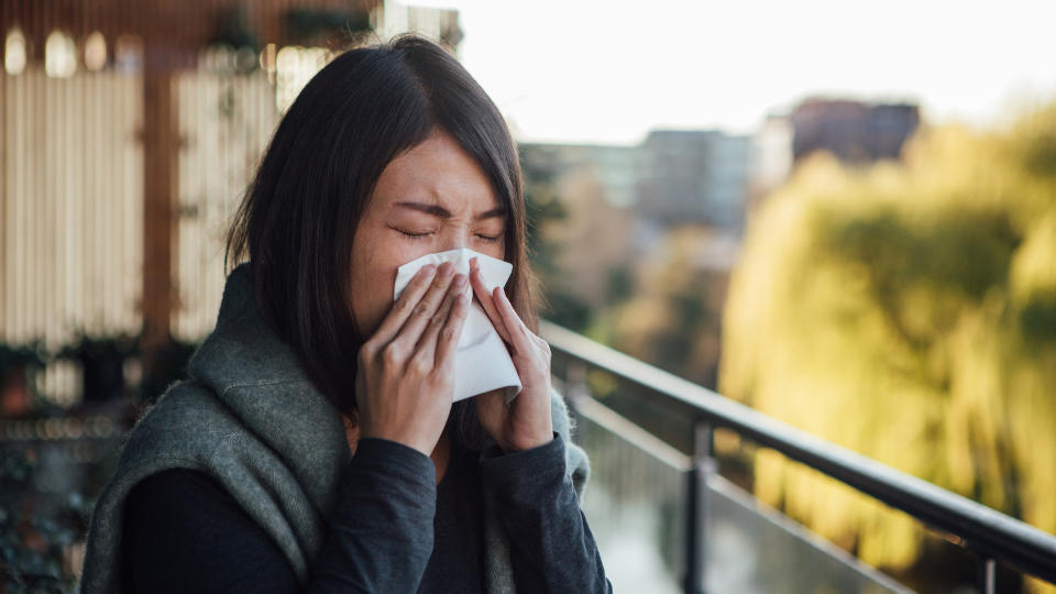 A photograph of a woman blowing her nose