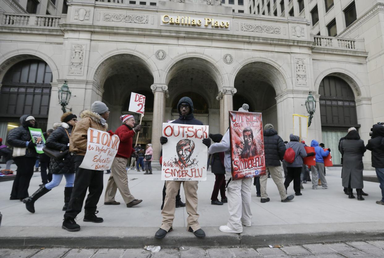 Protesters stand outside Cadillac Place, Monday, Jan. 25, 2016, in Detroit, where a judge is hearing arguments in a case that could force teachers to stop skipping school. The teachers' so-called sick-outs have repeatedly forced the district to close schools during the past two weeks, keeping thousands of students at home, so in a bid to stop the absences, the district filed a lawsuit. Teachers are upset over pay, class sizes, building conditions and Gov. Rick Snyder's plan to overhaul the district. (AP Photo/Carlos Osorio)
