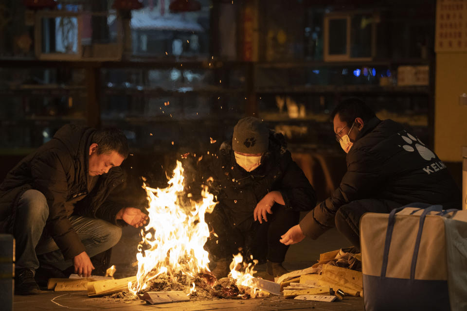 Residents burn paper money for the deceased on the street in Beijing, Wednesday, Dec. 28, 2022. China is on a bumpy road back to normal life as schools, shopping malls and restaurants fill up again following the abrupt end of some of the world's most severe restrictions even as hospitals are swamped with feverish, wheezing COVID-19 patients. (AP Photo/Ng Han Guan)