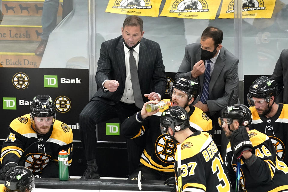 Boston Bruins head coach Bruce Cassidy, center, instructs his team during a timeout in the third period of Game 5 against the New York Islanders during an NHL hockey second-round playoff series, Monday, June 7, 2021, in Boston. (AP Photo/Elise Amendola)