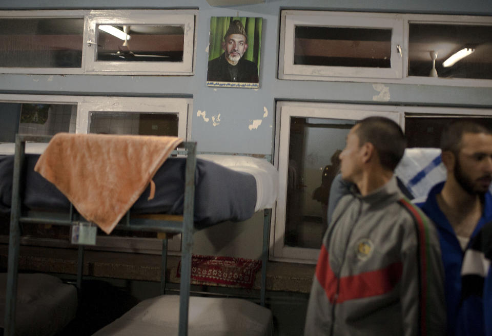 In this Oct. 15, 2012 photo, an Afghan police recruit looks at a picture of President Hamid Karzai hung above beds in his sleeping quarters at the National Police Academy in Kabul, Afghanistan. Afghans go to the polls April 5, 2014 to choose a new president, and that in itself may one day be considered Karzai’s greatest achievement. (AP Photo/Anja Niedringhaus)