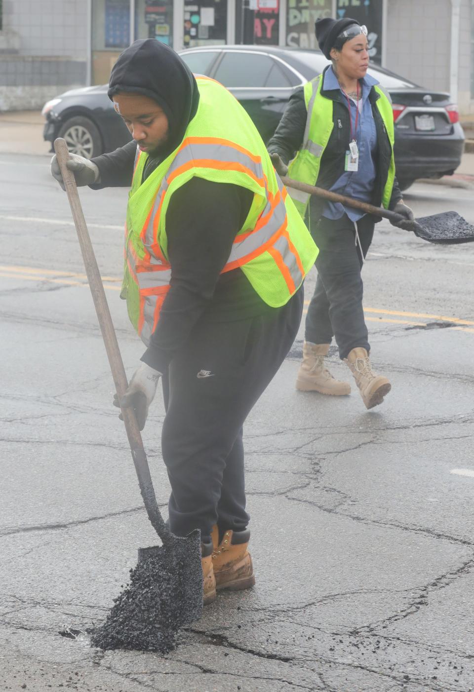 City of Akron highway maintenance workers Amos Johnson and Shay Carter fill potholes on East Exchange Street in Akron.