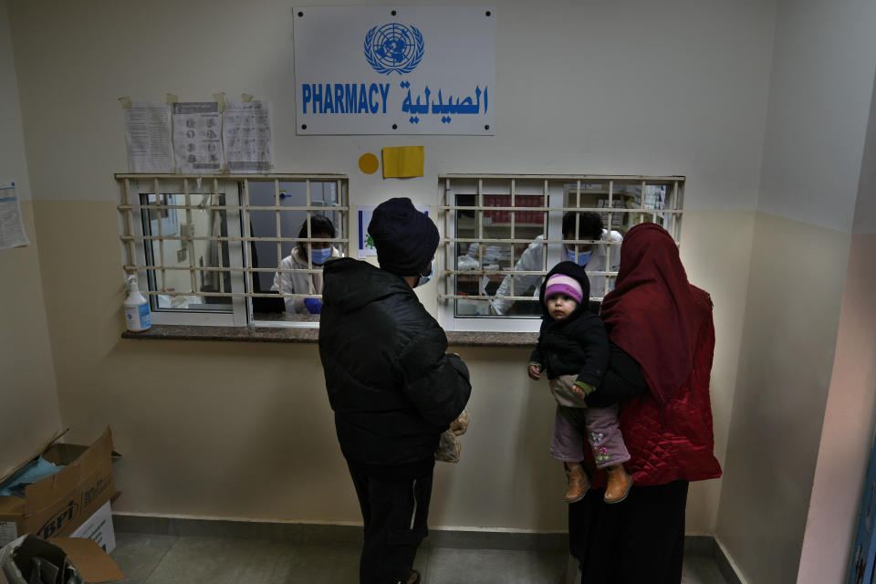 Palestinians receive medicine from a pharmacy run by the agency for Palestinian refugees, UNWRA, in the Bourj al-Barajneh Palestinian refugee camp, in Beirut, Lebanon, Tuesday, Jan. 18, 2022. UNRWA, appealed Wednesday to the international community to donate tens of millions of dollars to help improve living conditions for Palestinians in crisis-hit Lebanon. UNWRA is asking for an additional $87.5 million to provide Palestinian refugees with cash assistance to the poorest, cover hospital expenses, as well as transportation for children so that they can go to school. (AP Photo/Hussein Malla)