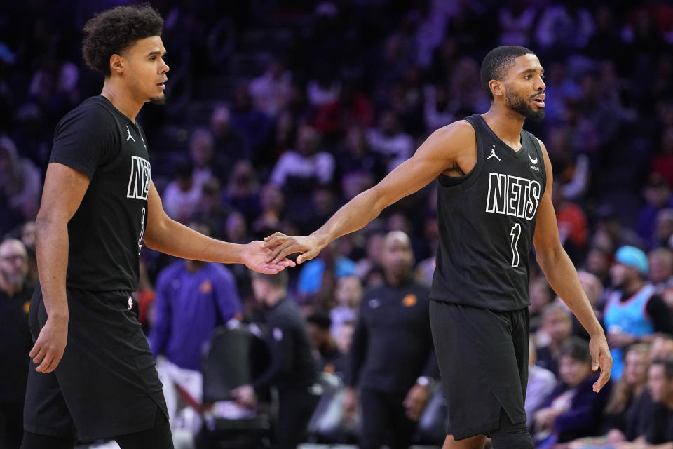 Brooklyn Nets forward Mikal Bridges (1) and orward Cameron Johnson (2) celebrate during a time out during the second half of an NBA basketball game against the Phoenix Suns, Wednesday, Dec. 13, 2023, in Phoenix. (AP Photo/Matt York)