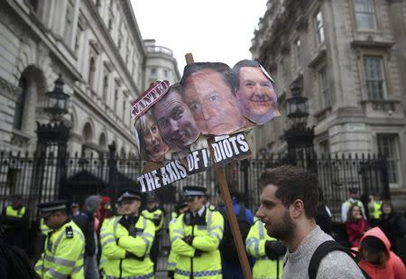 Demonstrators hold placards during a protest outside Downing Street in Whitehall, central London, Britain April 9, 2016. REUTERS/Neil Hall