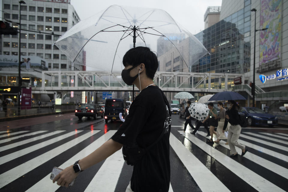 A man wearing a face mask to help curb the spread of the coronavirus walks across an intersection in a drizzle in Tokyo, Thursday, Sept. 2, 2021. (AP Photo/Hiro Komae)