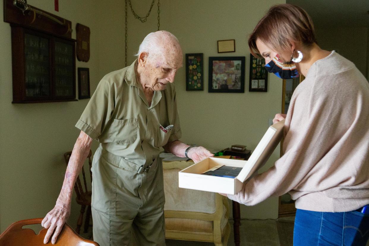 Crosby "Bing" Powell, 96, looks into a box of his World War II medals, which was delivered to him Friday afternoon in Topeka, Kansas, by Mikell Burr. Burr found his medals, dog tags and other artifacts from his time in the Army at a box in her home, which Powell had lived in previously.