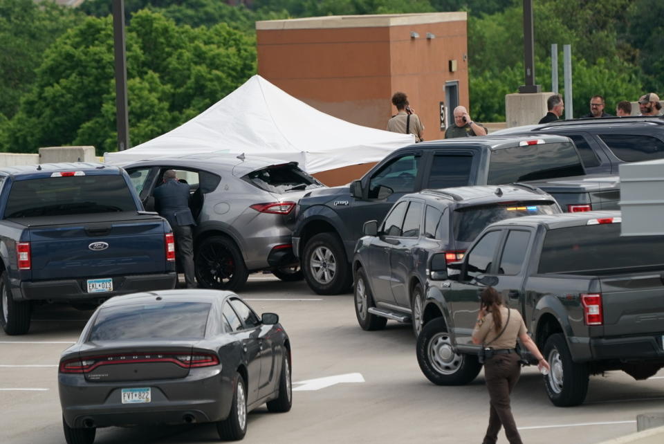 An investigator goes through the scene of crash believed to be part of an officer involved shooting on the top of a parking ramp in Minneapolis, Thursday June 3, 2021. One person was killed Thursday when authorities who were part of a task force that included U.S. Marshals fired their weapons after the person displayed a handgun in Minneapolis' Uptown neighborhood, the U.S. Marshals said. (Renee Jones Schneider/Star Tribune via AP)