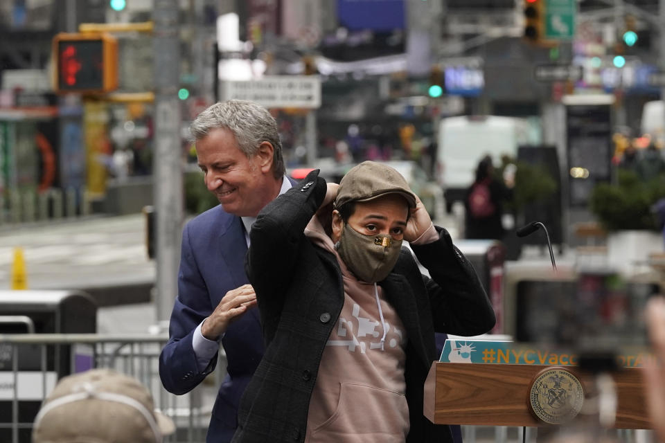 El actor Lin-Manuel Miranda, derecha, y el alcalde de Nueva York Bill de Blasio caminan en el podium antes del discurso de Miranda en Times Square después de nacer un recorrido inaugural del centro de vacunación COVID-19 Broadway en Nueva York el lunes 12 de abril de 2021. (Foto AP/Richard Drew)