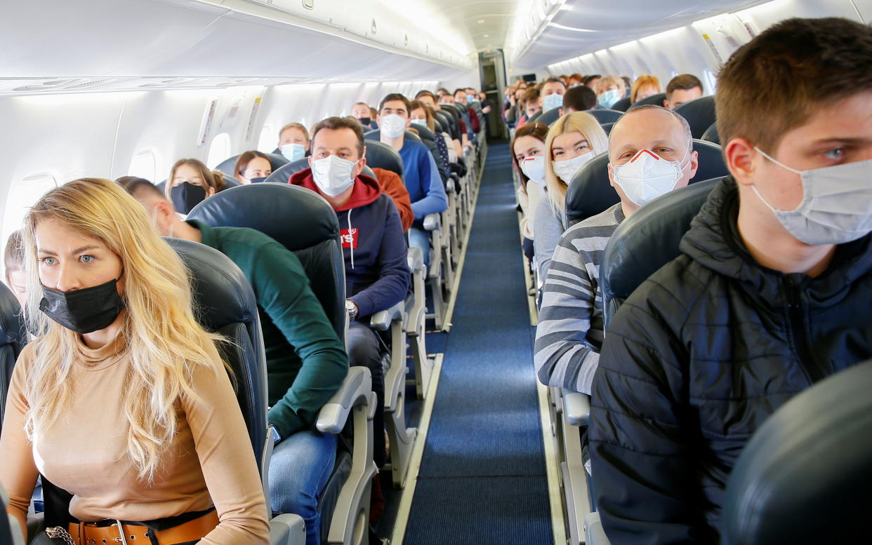 Passengers wear protective face masks onboard a plane during a tour to the Chernobyl exclusion zone, Ukraine April 3, 2021. Ukraine International Airlines made a special offer marking the 35th anniversary of the Chernobyl nuclear disaster. Tourists get a bird's eye view of abandoned buildings in the ghost town of Pripyat and the massive domed structure covering a reactor of the Chernobyl Nuclear Power Plant that exploded on April 26, 1986. Picture taken April 3, 2021. REUTERS/Gleb Garanich