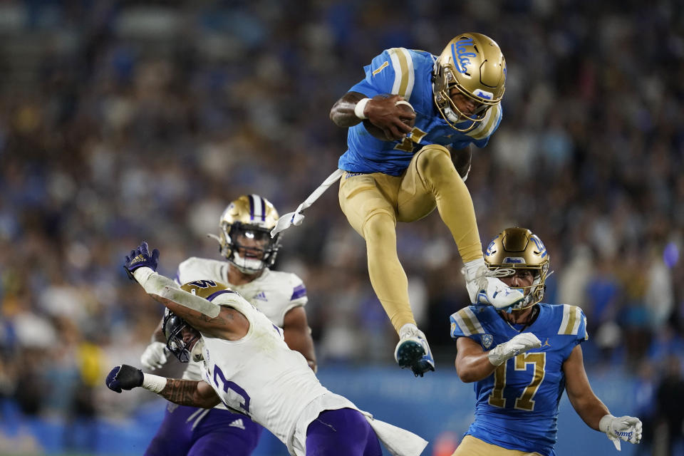 UCLA quarterback Dorian Thompson-Robinson, top, leaps over Washington linebacker Kamren Fabiculanan during the first half of an NCAA college football game Friday, Sept. 30, 2022, in Pasadena, Calif. (AP Photo/Marcio Jose Sanchez)