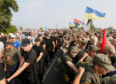 Participants take part in a procession organized by the Ukrainian Orthodox Church of the Moscow Patriarchate, petitioning for peace while accompanied by police officers (C), as members of the Ukrainian national guard (R) block pro-Ukrainian activists, in the city of Boryspil outside Kiev, Ukraine July 25, 2016. Picture taken July 25, 2016. REUTERS/Valentyn Ogirenko