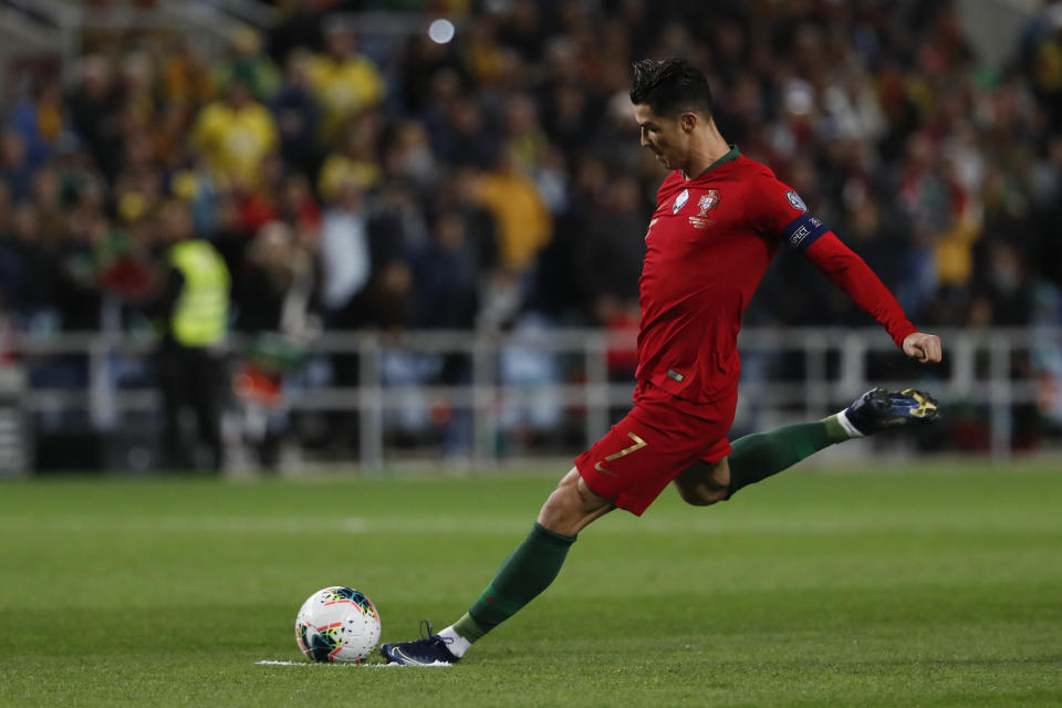 Portugal's Cristiano Ronaldo shoots a free kick during the Euro 2020 group B qualifying soccer match between Portugal and Lithuania at the Algarve stadium outside Faro, Portugal, Thursday, Nov. 14, 2019. Ronaldo scored a hat trick in Portugal's 6-0 victory. (AP Photo/Armando Franca)