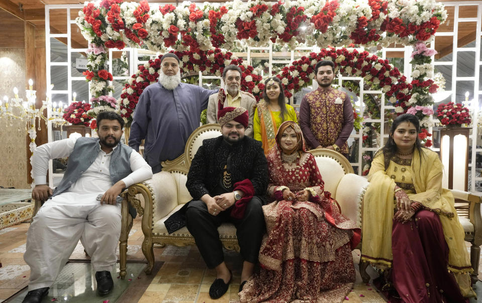 Pakistani bride Dua Khan and groom Asher Khan pose for photo with their other family members during their wedding ceremony at Radiance banqueting hall, in Karachi, Pakistan, Saturday, Jan. 27, 2024. There's a scrum of people trying to get photos with the married couple at the Radiance banqueting hall in a middle-class Karachi neighborhood . (AP Photo/Fareed Khan)