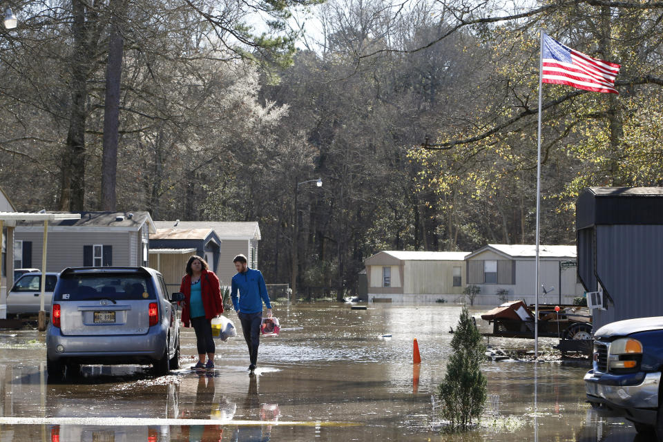 Jacob Goolsby, right, assists his neighbor Jessica Otto carry some of her belongings to her vehicle as they evacuate the Harbor Pines Mobile Home Community in Ridgeland, Miss., Friday, Feb. 14, 2020. The community is part of a subdivision that the mayor ordered to be evacuated Thursday evening. Officials estimate the flooding along the Pearl River to be the worst in Jackson and some neighboring communities since 1983. (AP Photo/Rogelio V. Solis)