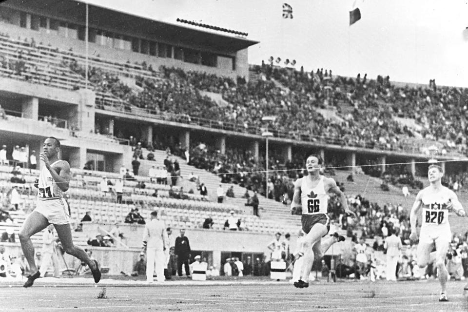 FILE - In this Aug. 4, 1936, file photo, American athlete Jesse Owens, left, breaks the tape in a record time of 21.1 seconds in the elimination heats of the men's 200-meter race at the Olympic Games race in Berlin, Germany. Scars of World War II and relics from its Nazi past are preserved at Berlin's Olympiastadion. When Spain plays England in the European Championship final, they will be playing in a stadium that doesn't hide it was built by the Nazis for the 1936 Olympic Games. (AP Photo/File)