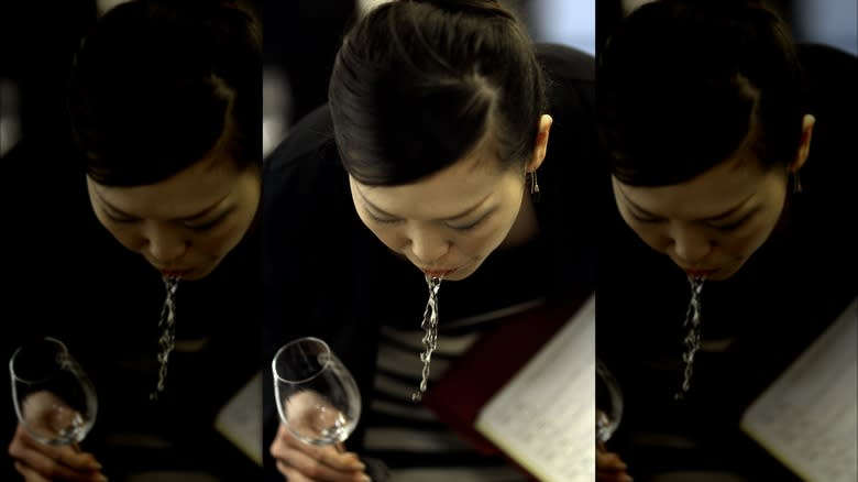 Woman spitting white wine