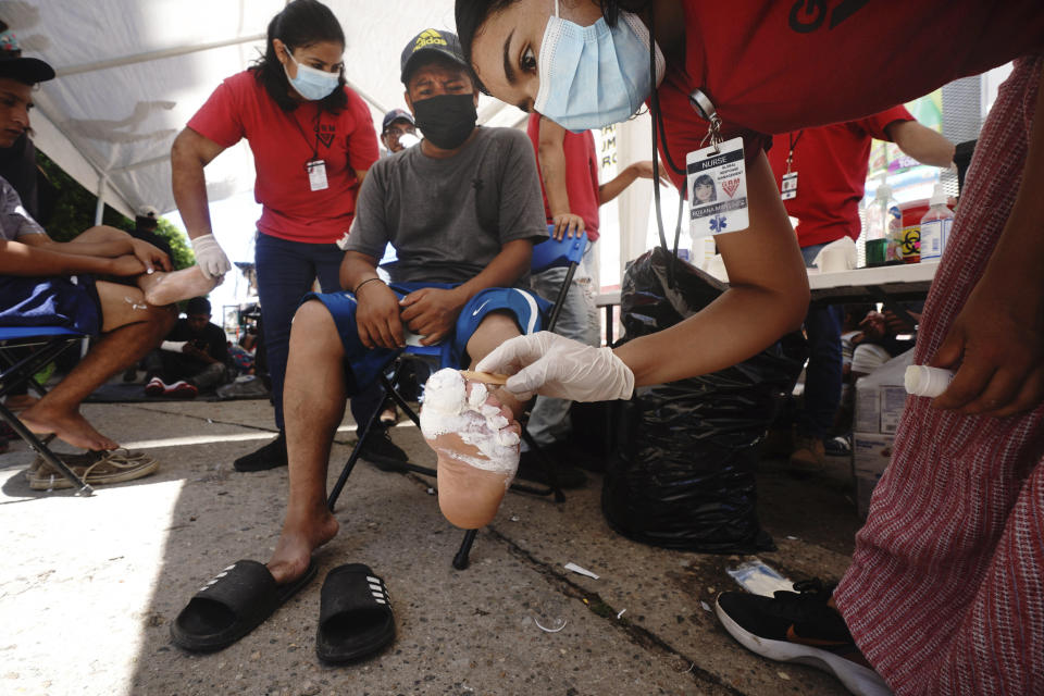 A volunteer providing first aide, wraps the foot of a migrant who is part of a caravan taking a day of rest before continuing their trek across southern Mexico to the U.S. border, in Huixtla, Chiapas state, Mexico, Tuesday, Oct. 26, 2021. (AP Photo/Marco Ugarte)