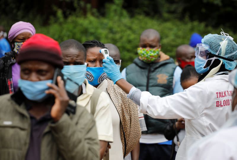 A health worker takes the temperature of a person standing in line for mass testing in an effort to stop the spread of the coronavirus disease (COVID-19) in the Kibera slum of Nairobi