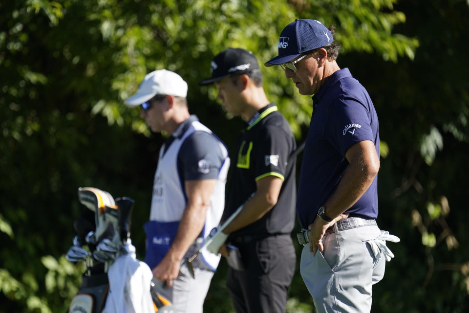 Phil Mickelson, right, Kevin Na, center, and their caddie observe a moment of silence on the 13th tee during the first round of the Charles Schwab Challenge golf tournament at the Colonial Country Club in Fort Worth, Texas, Thursday, June 11, 2020. Players at the 8:46 a.m. tee time paused to pay their respects to the memory of George Floyd for a moment of silence, prayer and reflection. (AP Photo/David J. Phillip)