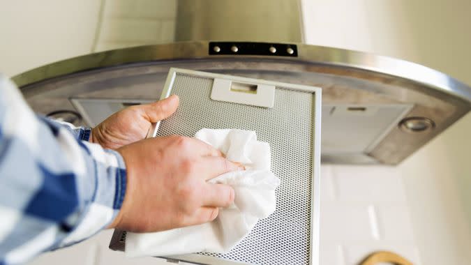 Man's hands cleaning aluminum mesh filter for cooker hood.