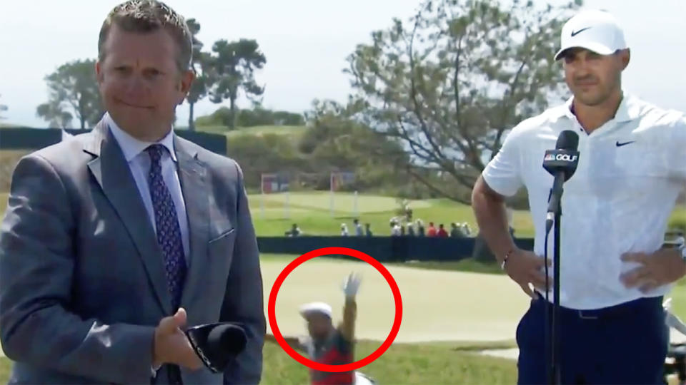 Bryson DeChambeau waves in the background while Books Koepka was in the middle of an interview.