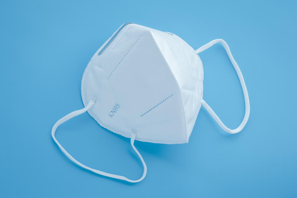 Surgical KN95 respirator, white protective medical face mask to cover the mouth and nose. Blue background. Covid-19 prevention, protection concept from oronavirus disease pandemic