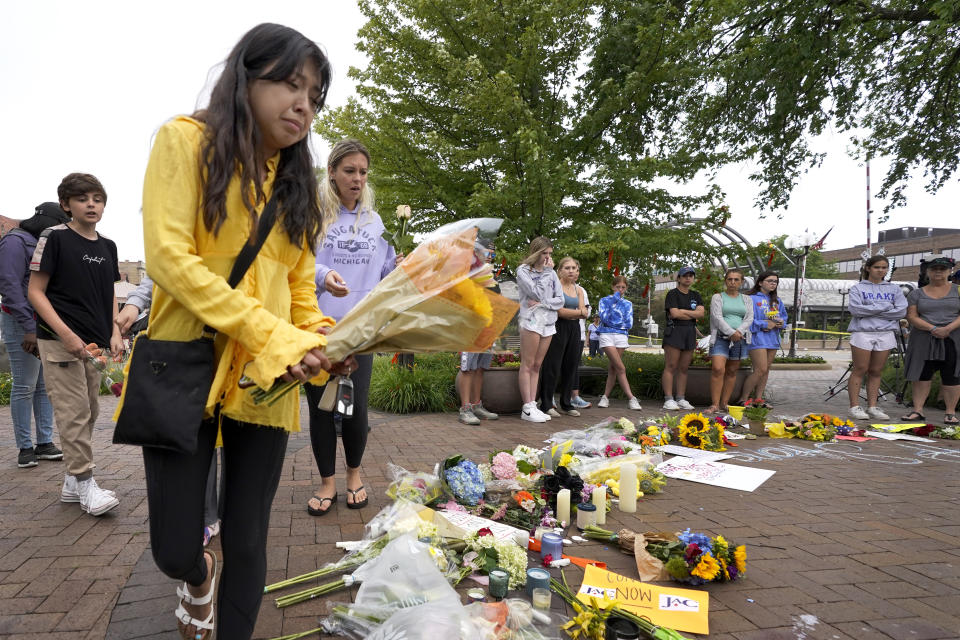 Yesenia Hernandez, granddaughter to Nicolas Toledo, who was killed during Monday's Highland Park., Ill., Fourth of July parade, brings flowers to a memorial for Toledo and six others who lost their lives in the mass shooting, Wednesday, July 6, 2022, in Highland Park. (AP Photo/Charles Rex Arbogast)