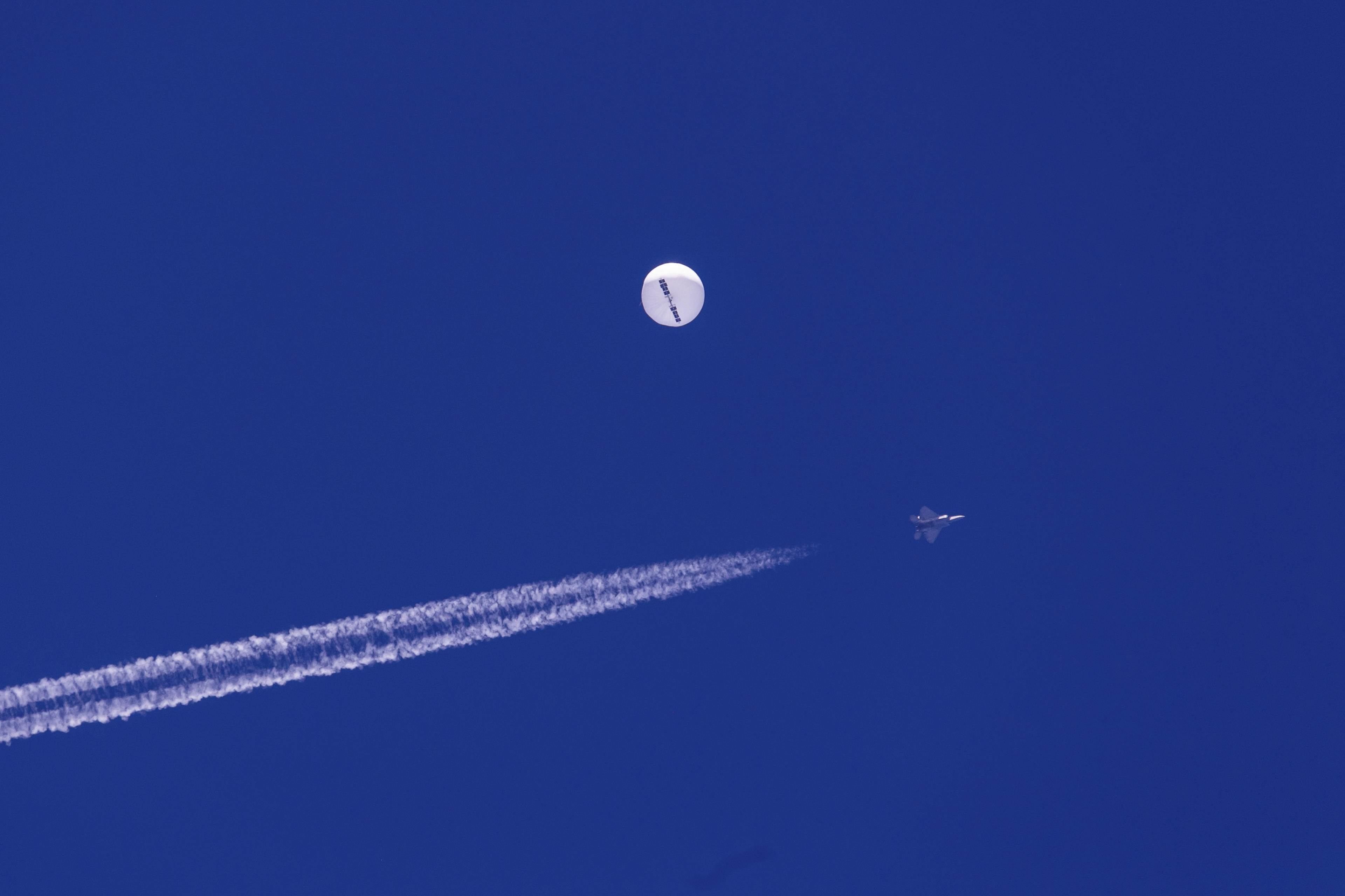 A jet flies by a suspected Chinese spy balloon as it floats off the coast near Myrtle Beach, S.C., in February 2023.  (Chad Fish via AP)