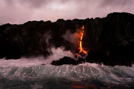 FILE PHOTO - Waves crash over lava as it flows into the ocean near Volcanoes National Park which is on the UNESCO World Heritage Natural List in Kalapana, Hawaii, U.S. on November 27, 2012. REUTERS/Hugh Gentry/File Photo