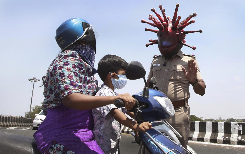 Police officer Rajesh Babu wears a helmet representing the coronavirus, and requests commuters to stay home during the 21-day countrywide lockdown that began Wednesday in Chennai, India, Saturday, March 28, 2020. The new coronavirus causes mild or moderate symptoms for most people, but for some, especially older adults and people with existing health problems, it can cause more severe illness or death. (AP Photo/R. Parthibhan)