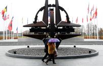 People hold umbrellas outside NATO headquarters in Brussels