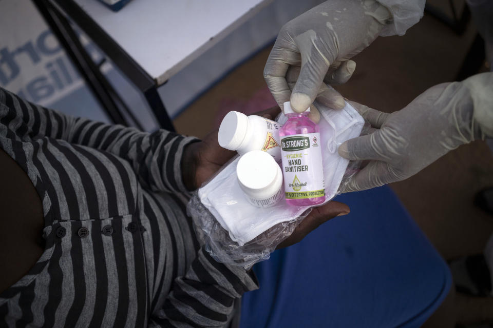 Nurse Nomautanda Siduna gives hand sanitizer and antiretroviral drugs to a patient in Ngodwana, South Africa, Thursday, July 2, 2020. Across Africa and around the world, the COVID-19 pandemic has disrupted the supply of antiretroviral drugs to many of the more than 24 million people who take them, endangering their lives. An estimated 7.7 million people in South Africa are HIV positive, the largest number in the world, and 62% of them take the antiretroviral drugs that suppress the virus and prevent transmission. (AP Photo/Bram Janssen)