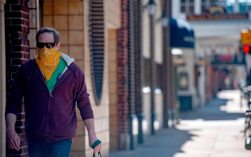 A man walks down College Avenue wearing a bandana for a mask on Monday, April 6, 2020.